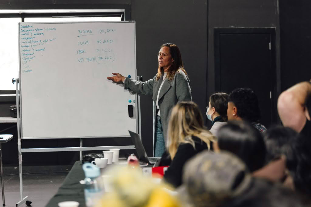 Auckland accountant standing at whiteboard explaining profit and loss concepts to workshop participants