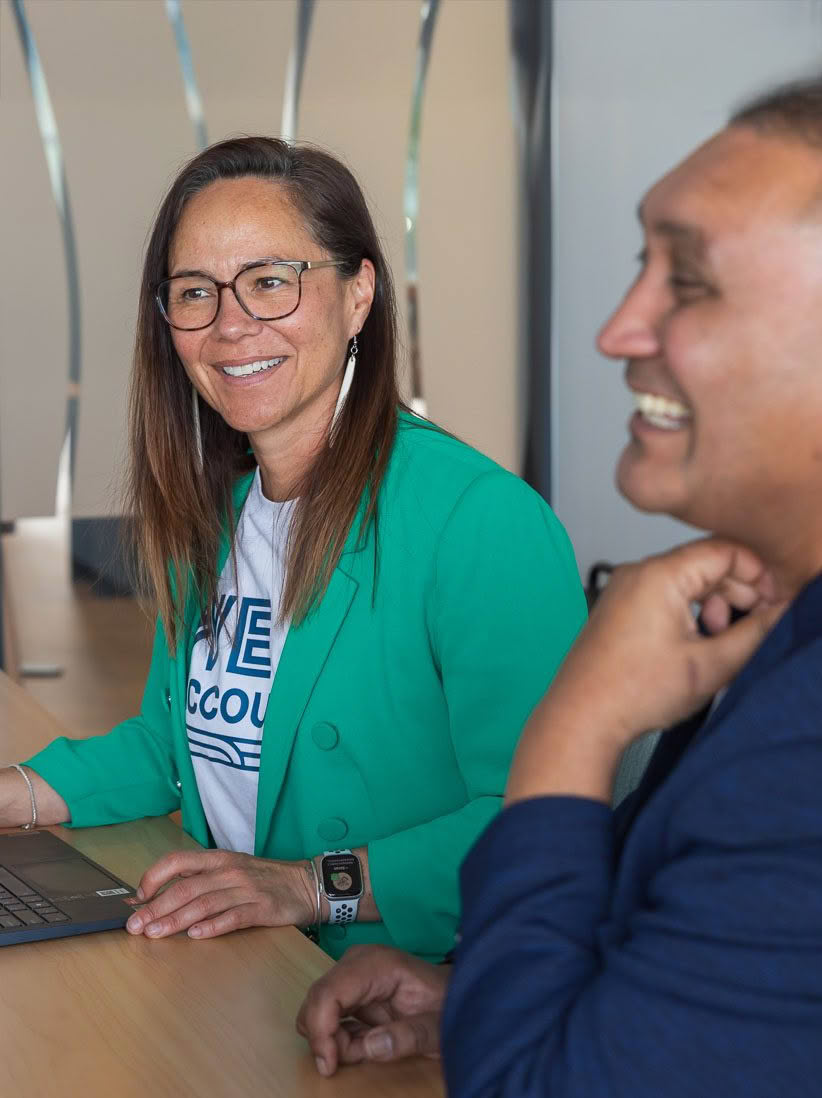 Accountant in green jacket at meeting discussing financial governance for Maori and Pacific non-for-profits